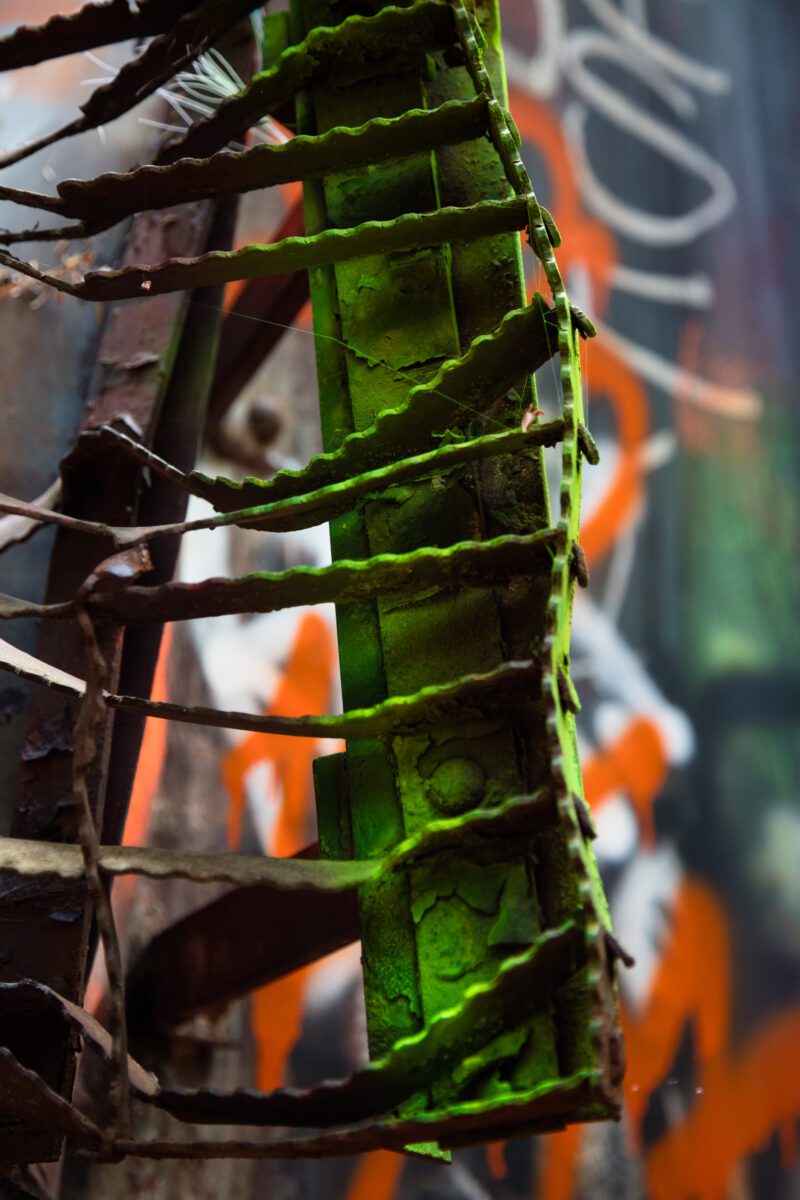 This striking print captures an unexpected fusion of art and derailment, where twisted metal meets vibrant graffiti, forming a unique green caterpillar.