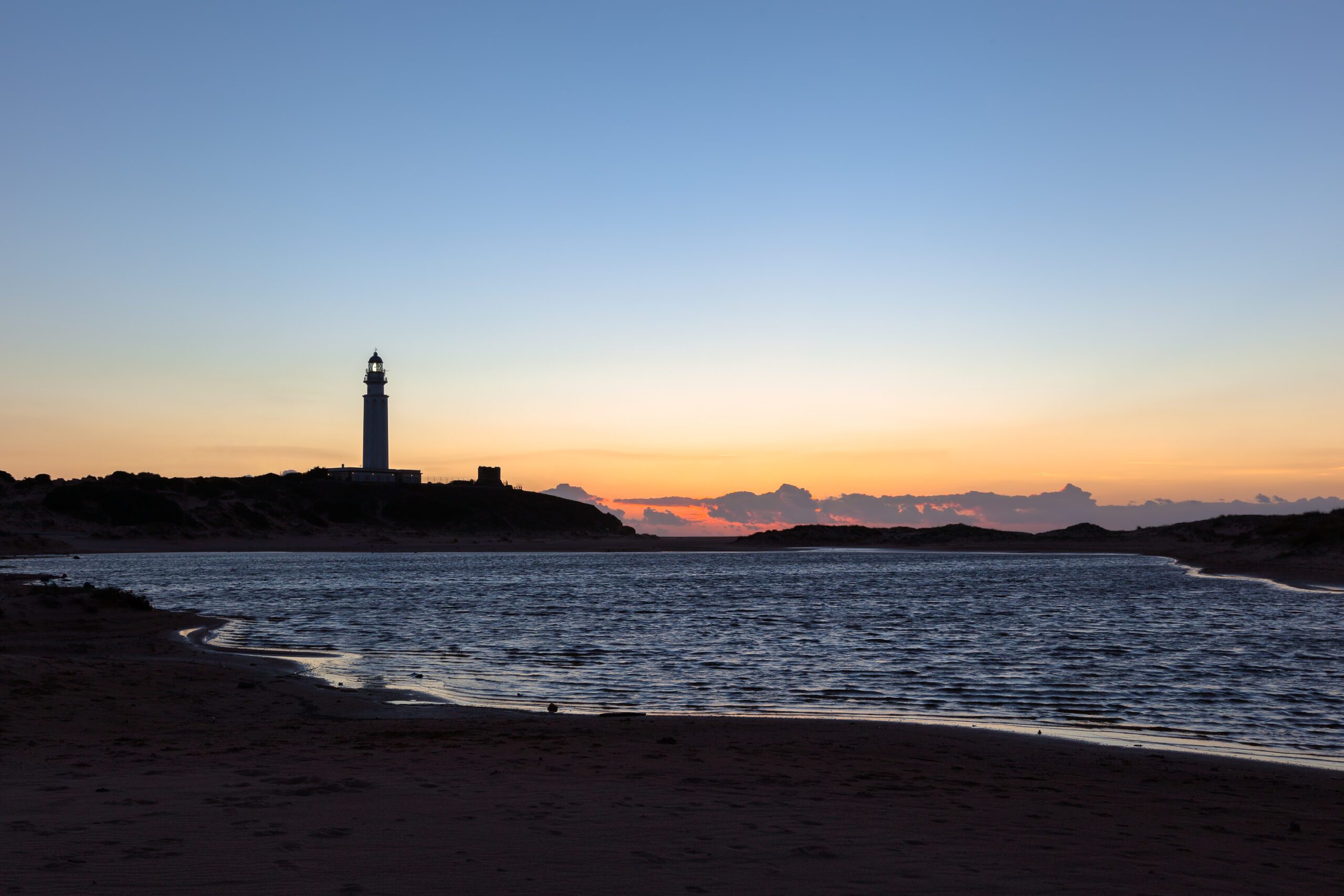A captivating depiction of Cape Trafalgar’s lighthouse, elegantly silhouetted against the canvas of a sunset sky,