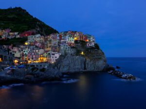 This striking image This image encapsulates a serene twilight moment in Manarola, where the first hints of evening lights begin to sprinkle the town, creating a magical ambiance. a solitary figure amidst the historic beauty of Cadiz, offering a tale of reflection and timelessness.