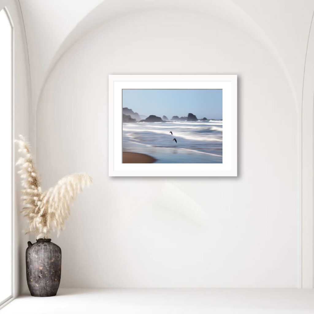 Experience the tranquility and grace captured in this striking image, portraying seagulls soaring over the vibrant waves at Indian Beach, Oregon.