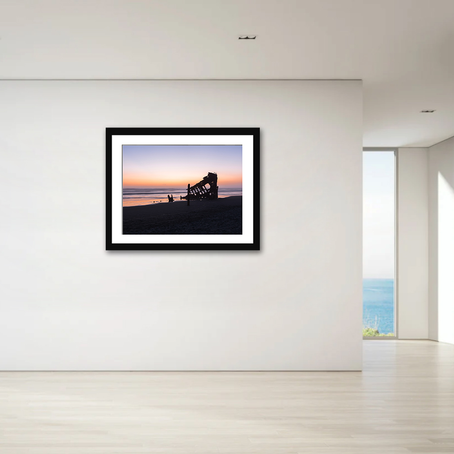 This print encapsulates a haunting yet breathtaking view of the Peter Iredale shipwreck, gloriously silhouetted against a vibrant sunset