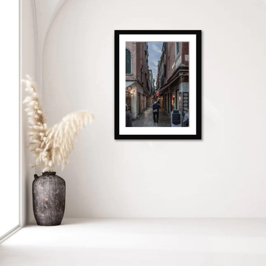 Man walking through historic Venetian alley at evening.