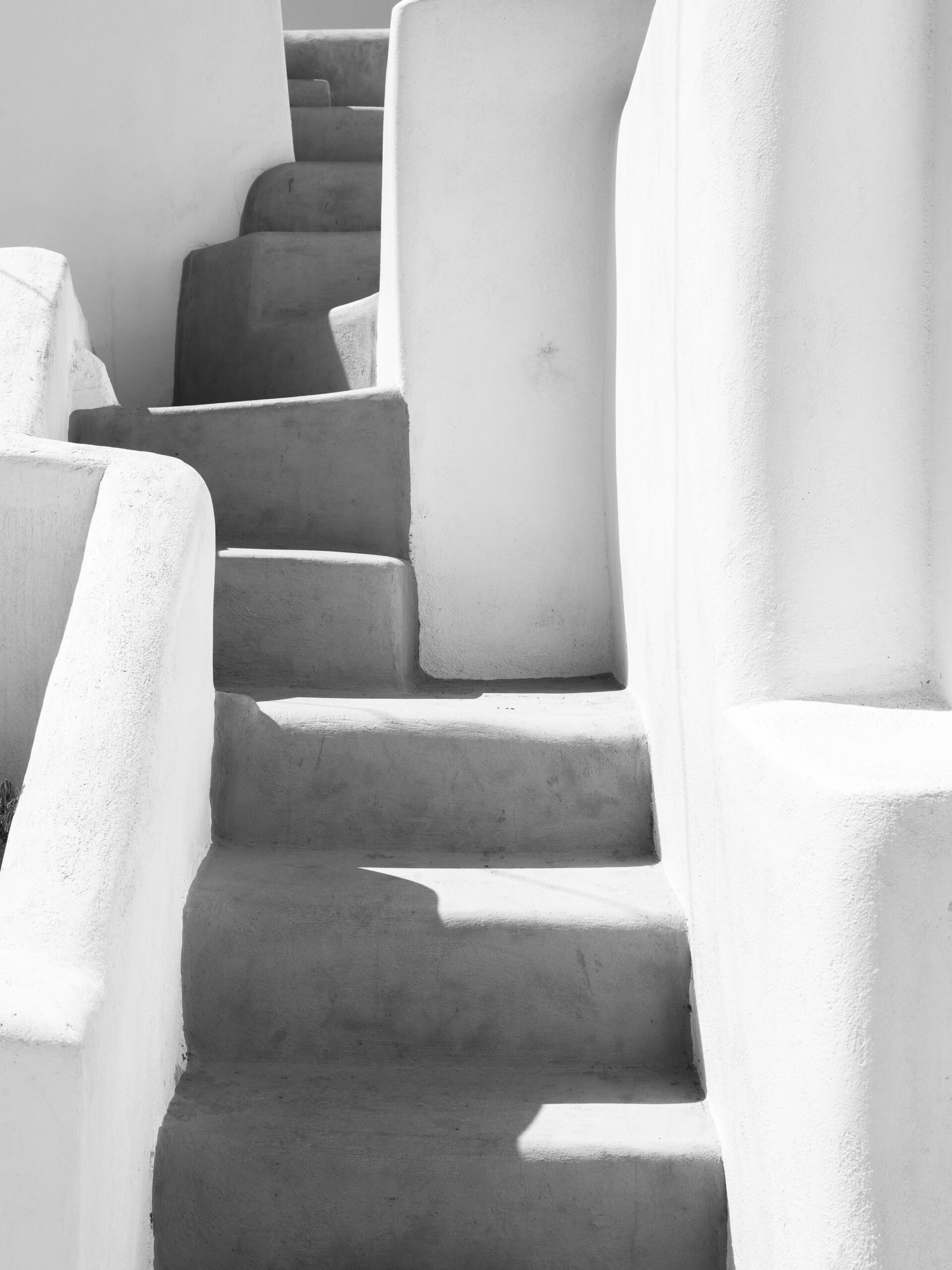 Black and white photo of an ancient staircase with shadows in Santorini, Greece.